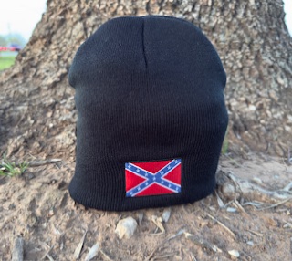 Black beanie featuring a centered Confederate battle flag patch, displayed upright outdoors in front of a tree.